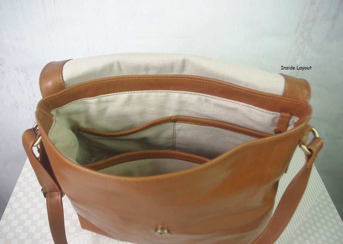 Brown leather handbag with beige interior on a white background