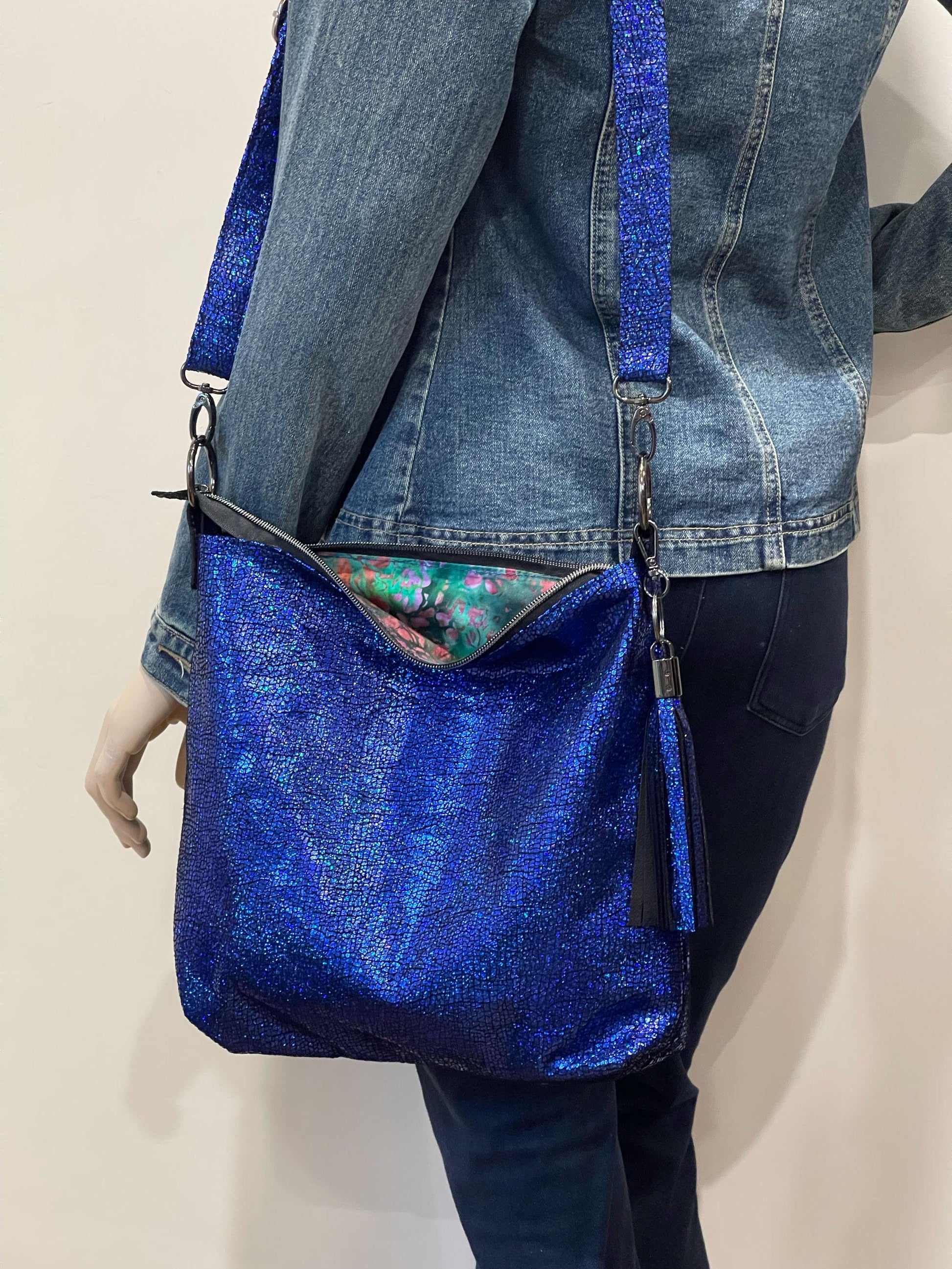 Blue glittery handbag worn by a mannequin against a neutral background