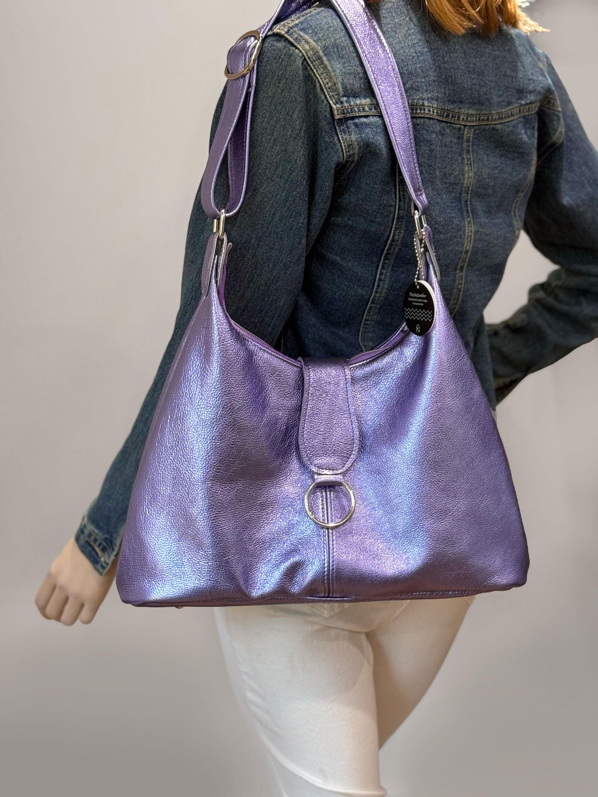 Purple handbag worn by a person against a neutral background