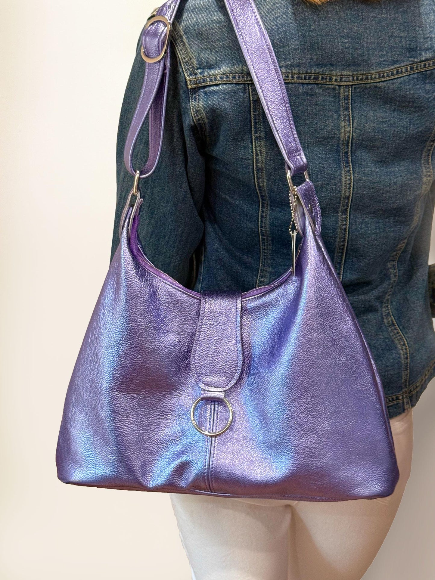 Purple handbag worn over the shoulder with a neutral background