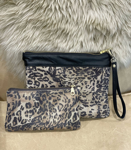 Two leopard print purses in small and medium with black accents on a fur background