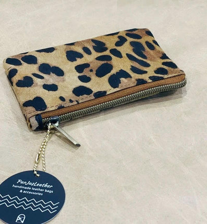 Leopard print zipper pouch with antique brass zipper with a visible brand tag on a light background