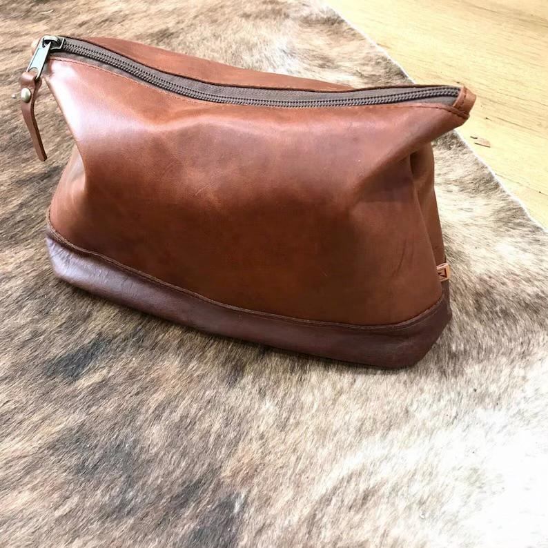 A brown leather toiletry bag with a zipper, perfect for all men