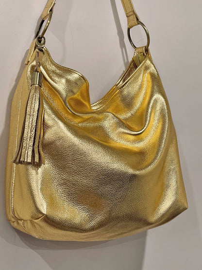 Gold metallic handbag with a tassel on a light gray background