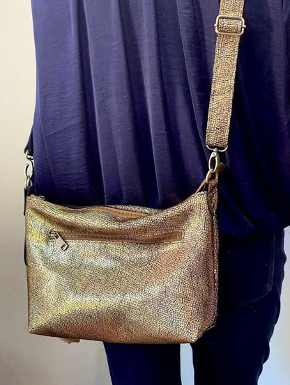 Gold metallic handbag worn over the shoulder with brass hardware and convenient zipper pocket