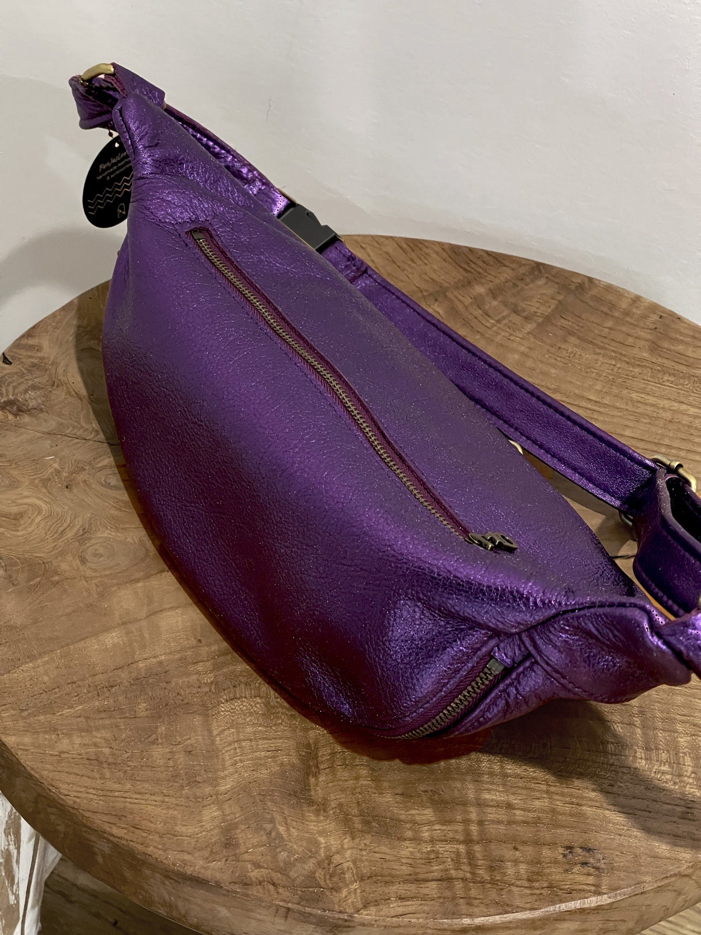 Purple waist bag on a wooden surface with a plain background
