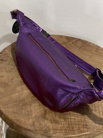 Purple waist bag on a wooden surface with a plain background