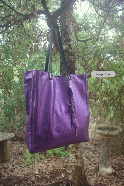Purple tote bag with black handles hanging from a tree in a forest setting