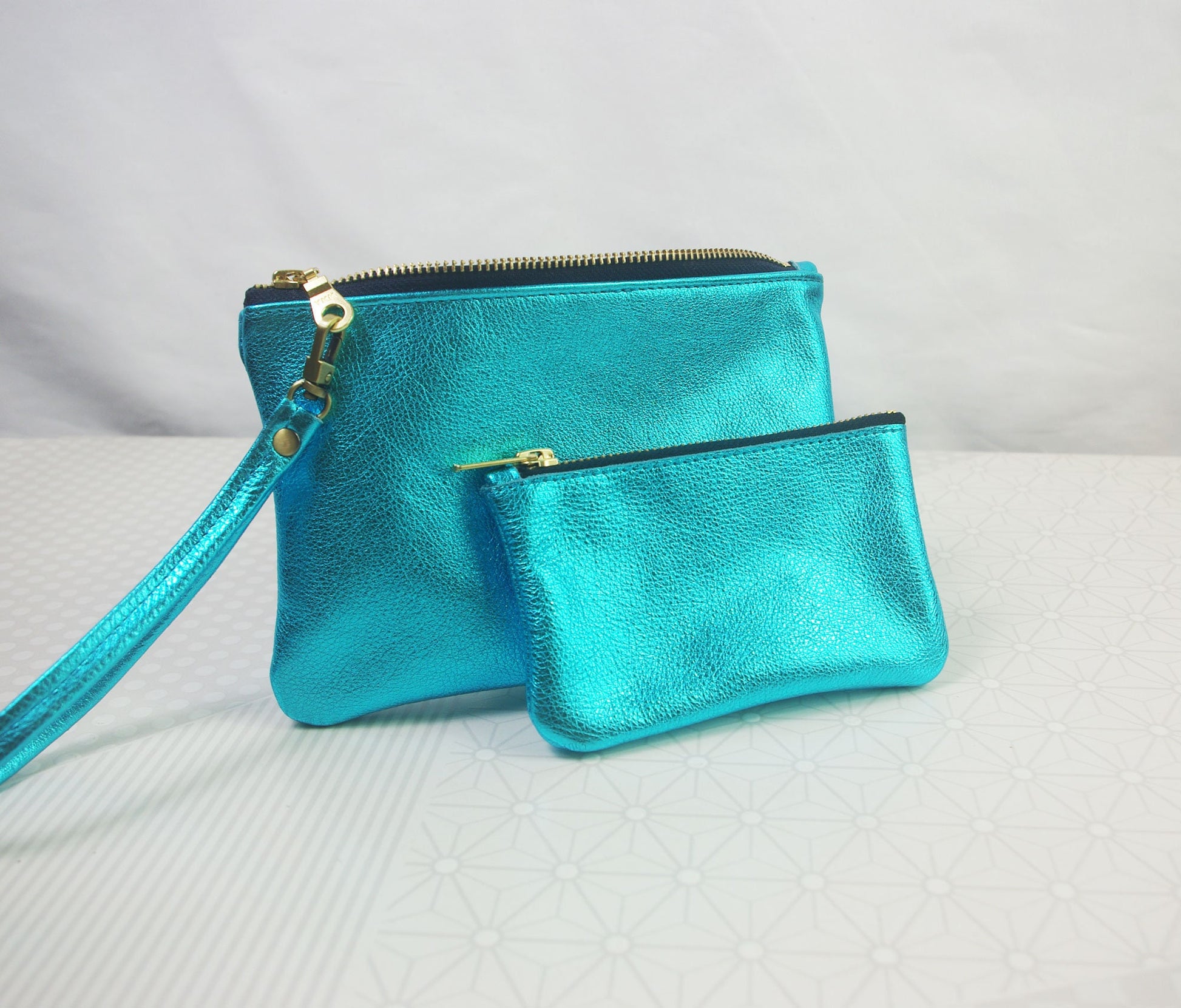 Turquoise clutch bag with matching zipper pouch on a light gray background