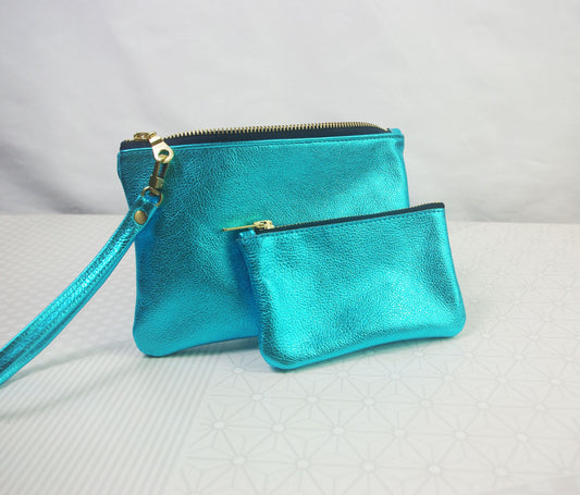 Turquoise clutch bag with matching zipper pouch on a light gray background
