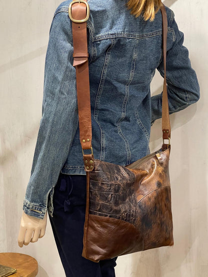 Person wearing a denim jacket with a combination brown leather shoulder bag.