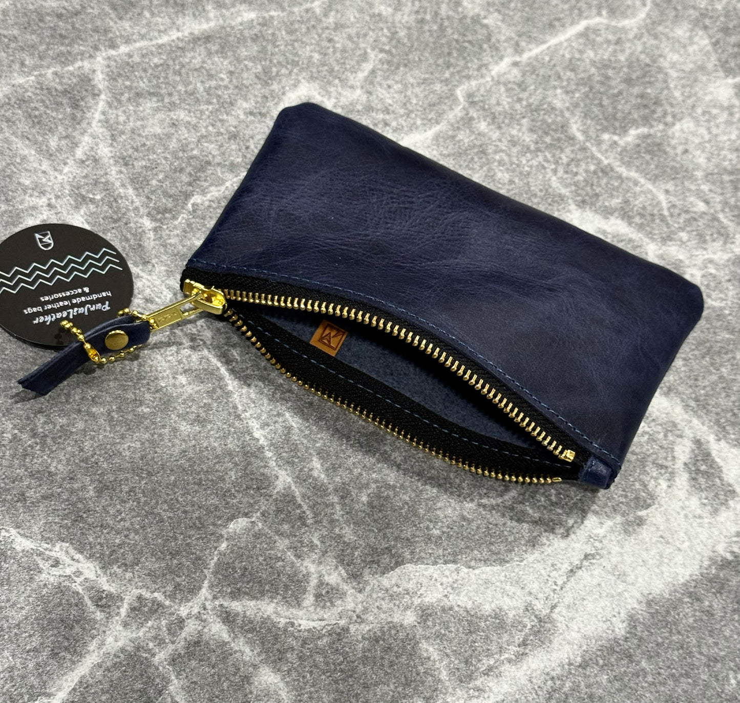 Navy blue zipper purse open with gold zipper and leather pull