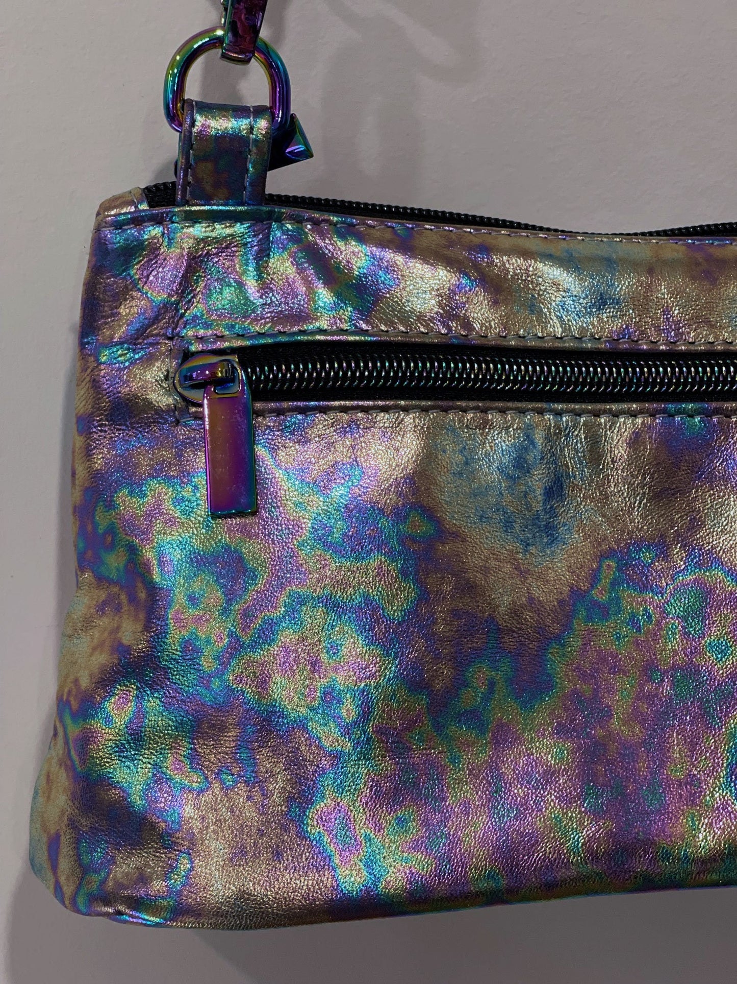 multi colour metallic pouch with a zipper pocket and zipper closure on a plain background
