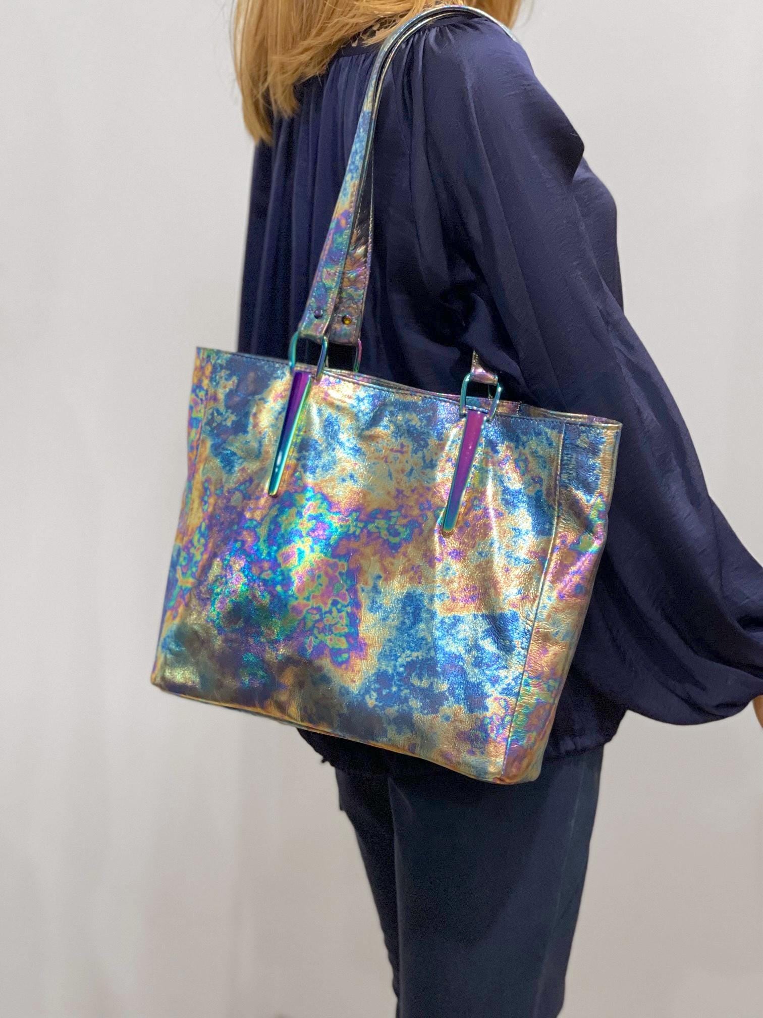 Person holding a colorful iridescent tote bag against a plain background