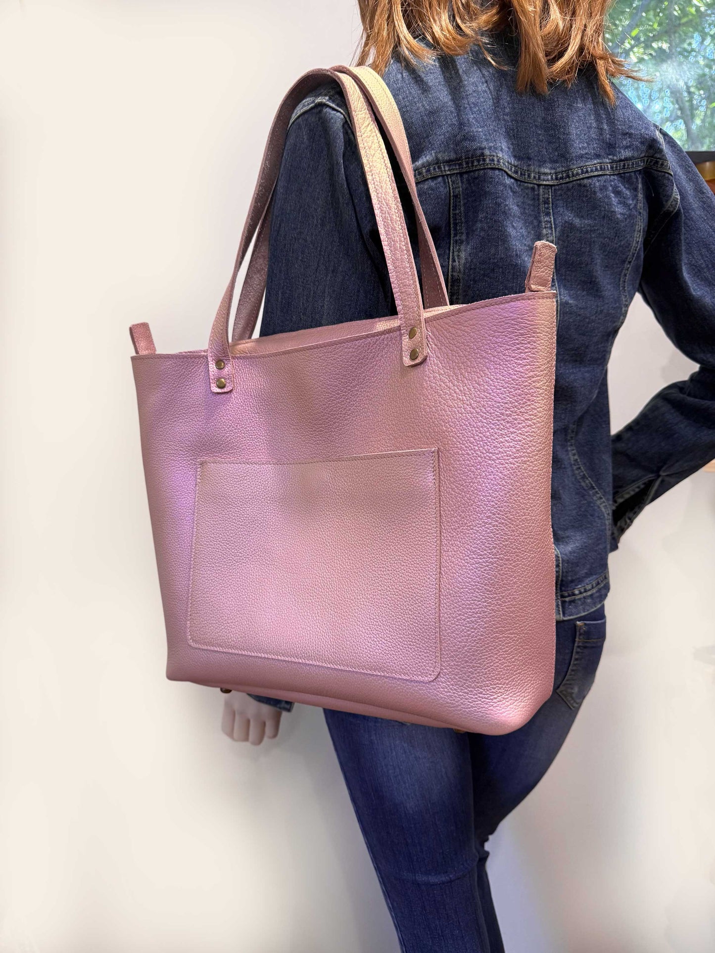 model carries pearlised pink leather tote on shoulder zipper closure