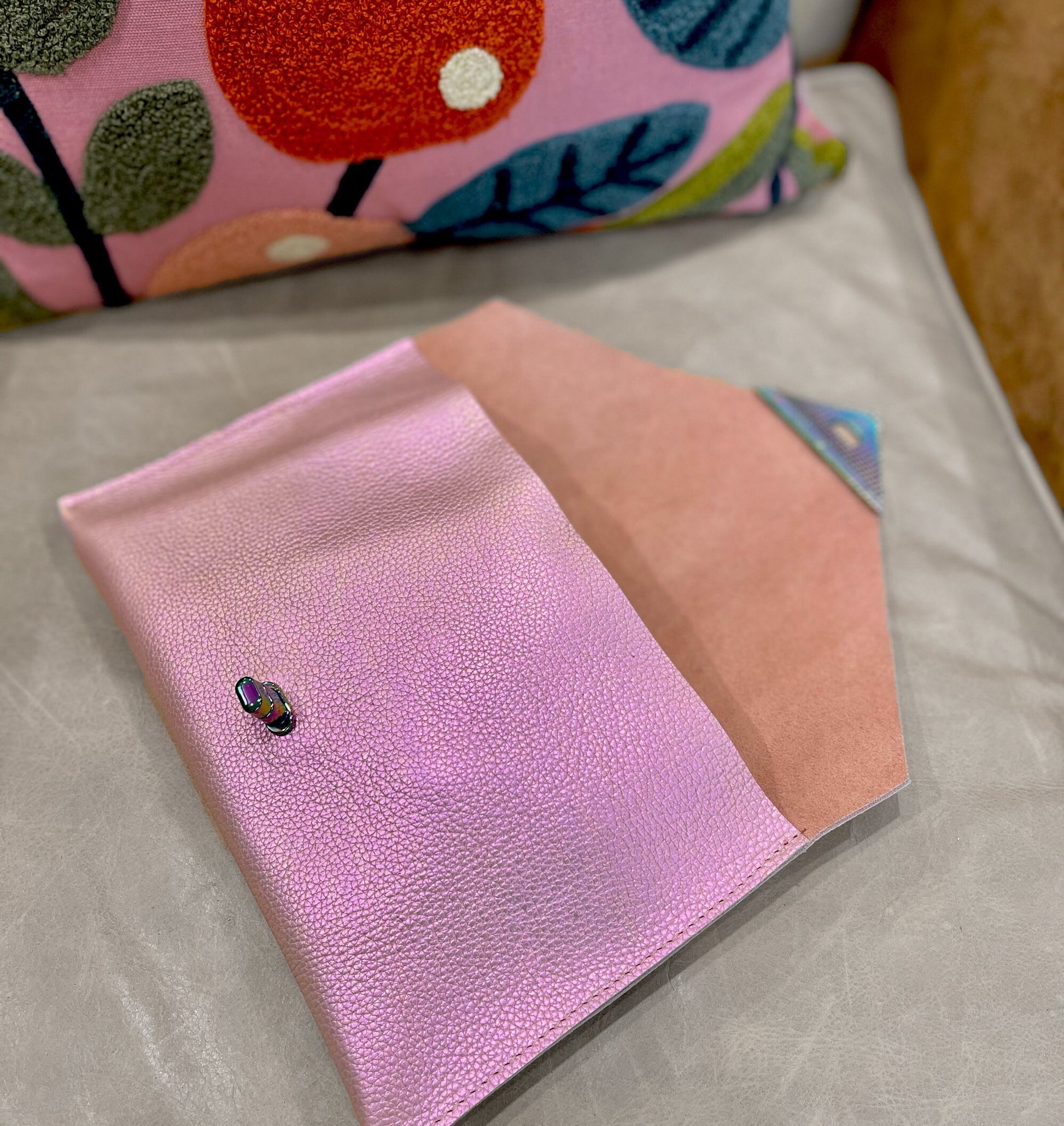 Pink and peach notebook with a small black and red object on a light gray surface.