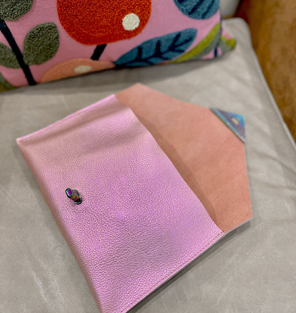 Pink and peach notebook with a small black and red object on a light gray surface.