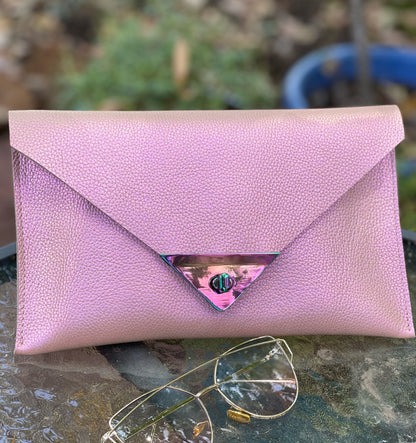 Pink clutch bag on a textured surface with sunglasses beside it