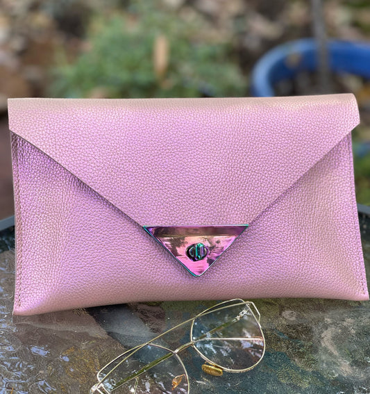 Pink clutch bag on a textured surface with sunglasses beside it