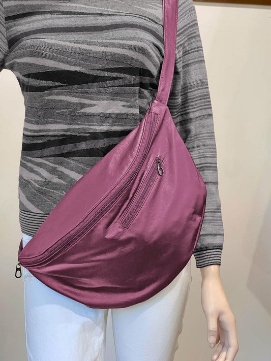 Person wearing a pink  sling bag over one shoulder against a neutral background