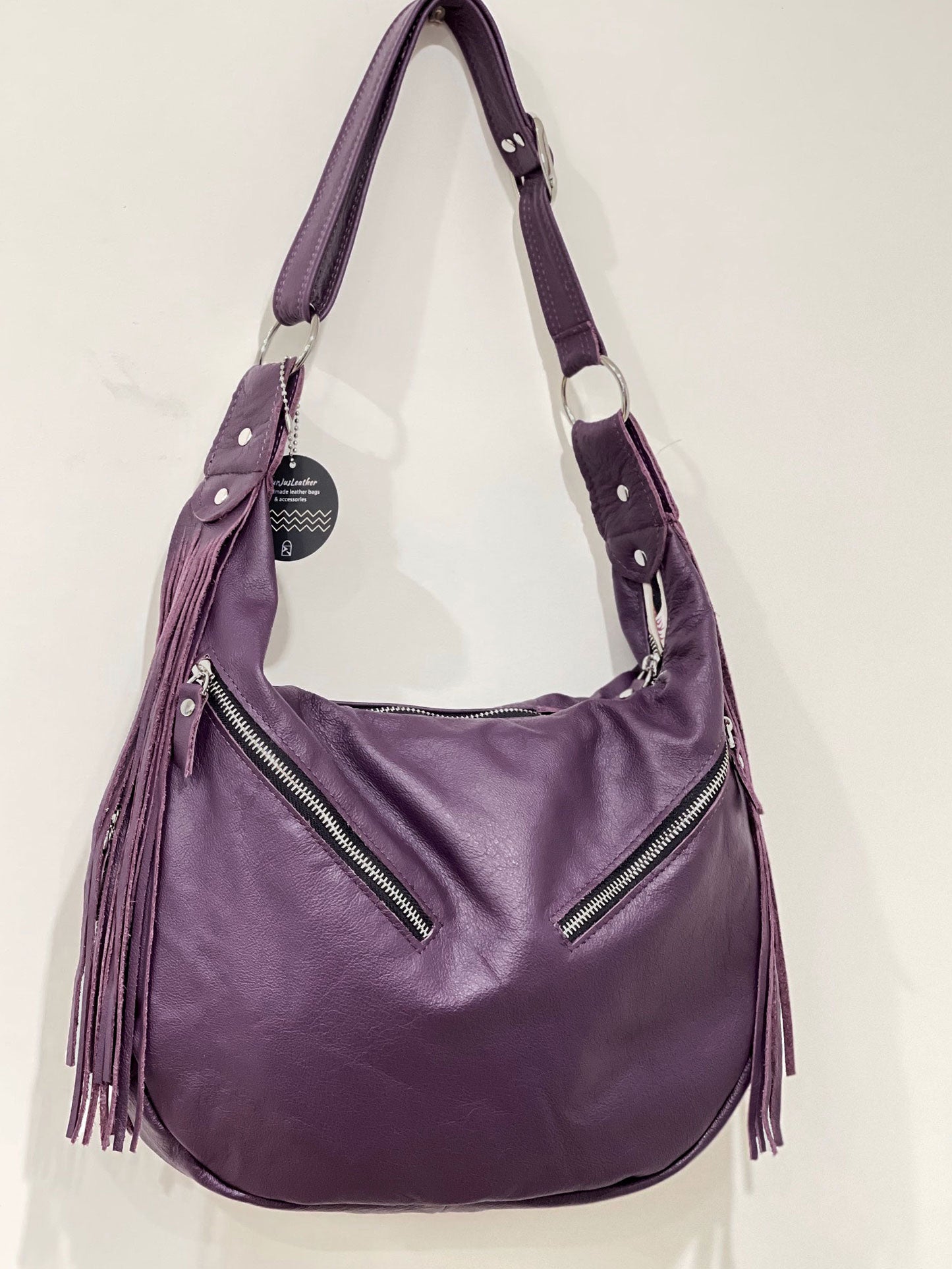 Purple handbag with fringe details on a white background
