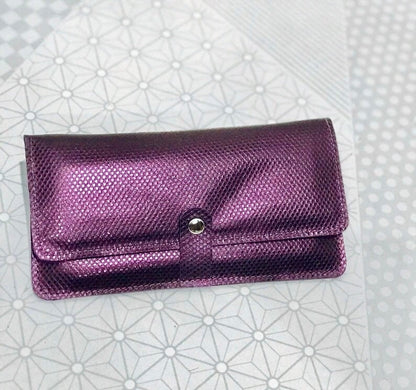 Purple textured clutch bag on a patterned white background