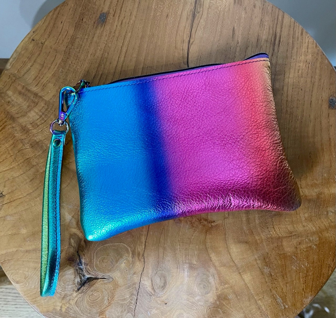 rainbow Gradient blue to pink pouch with a strap on a wooden surface