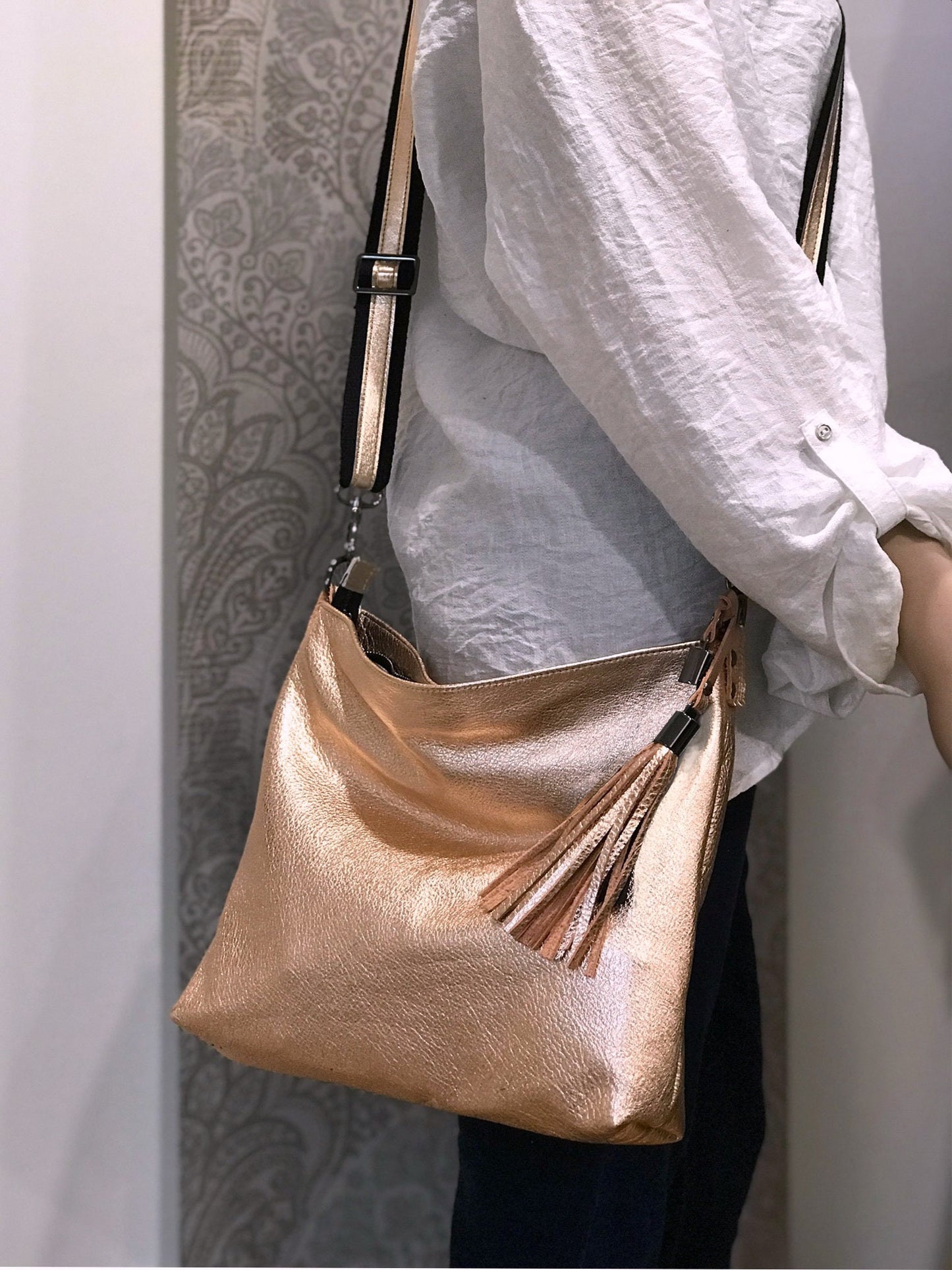 Person holding a gold handbag with a tassel against a neutral background
