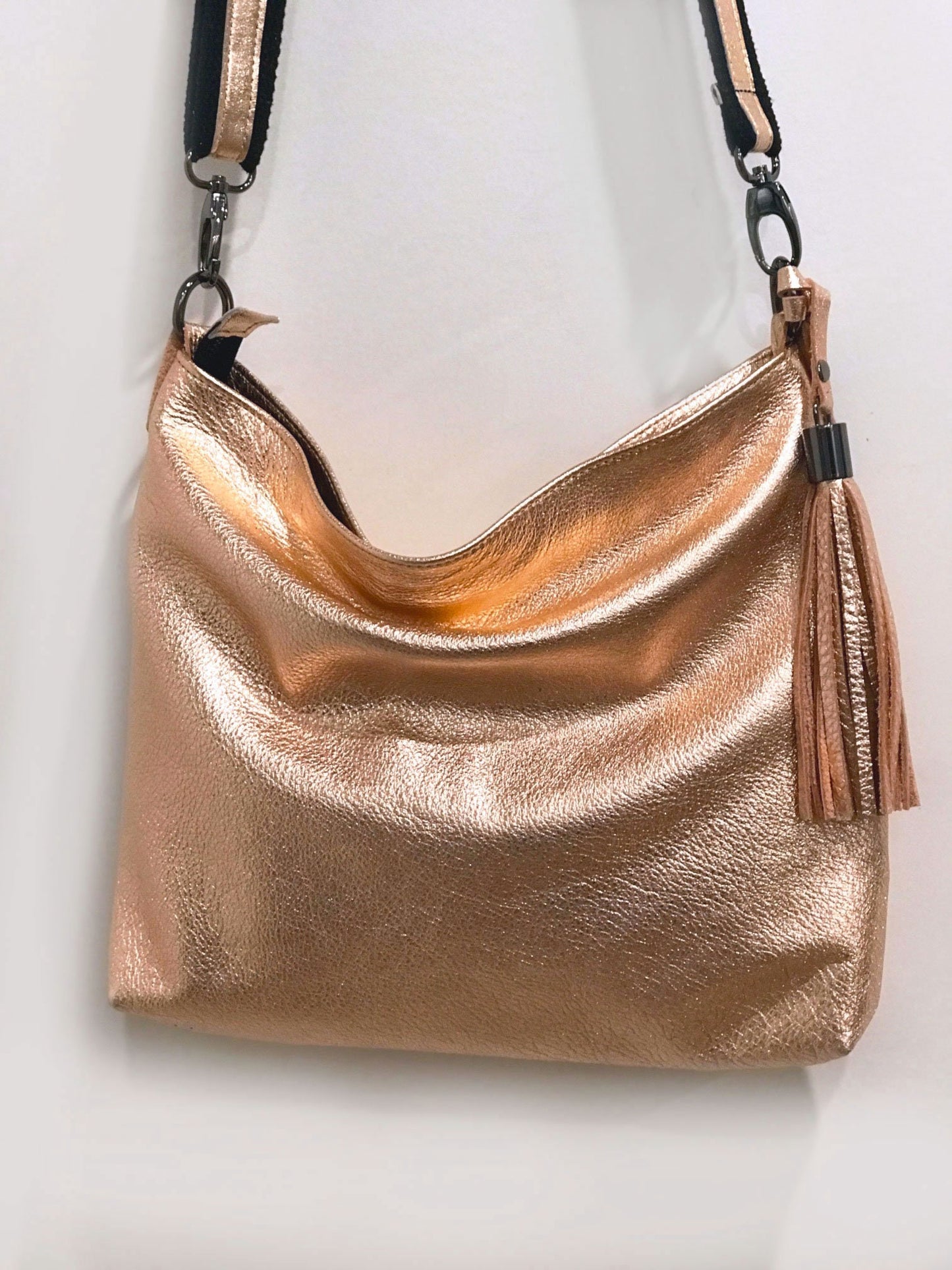 Rose gold handbag with a tassel on a light background