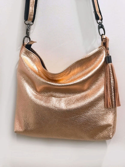 Rose gold handbag with a tassel on a light background