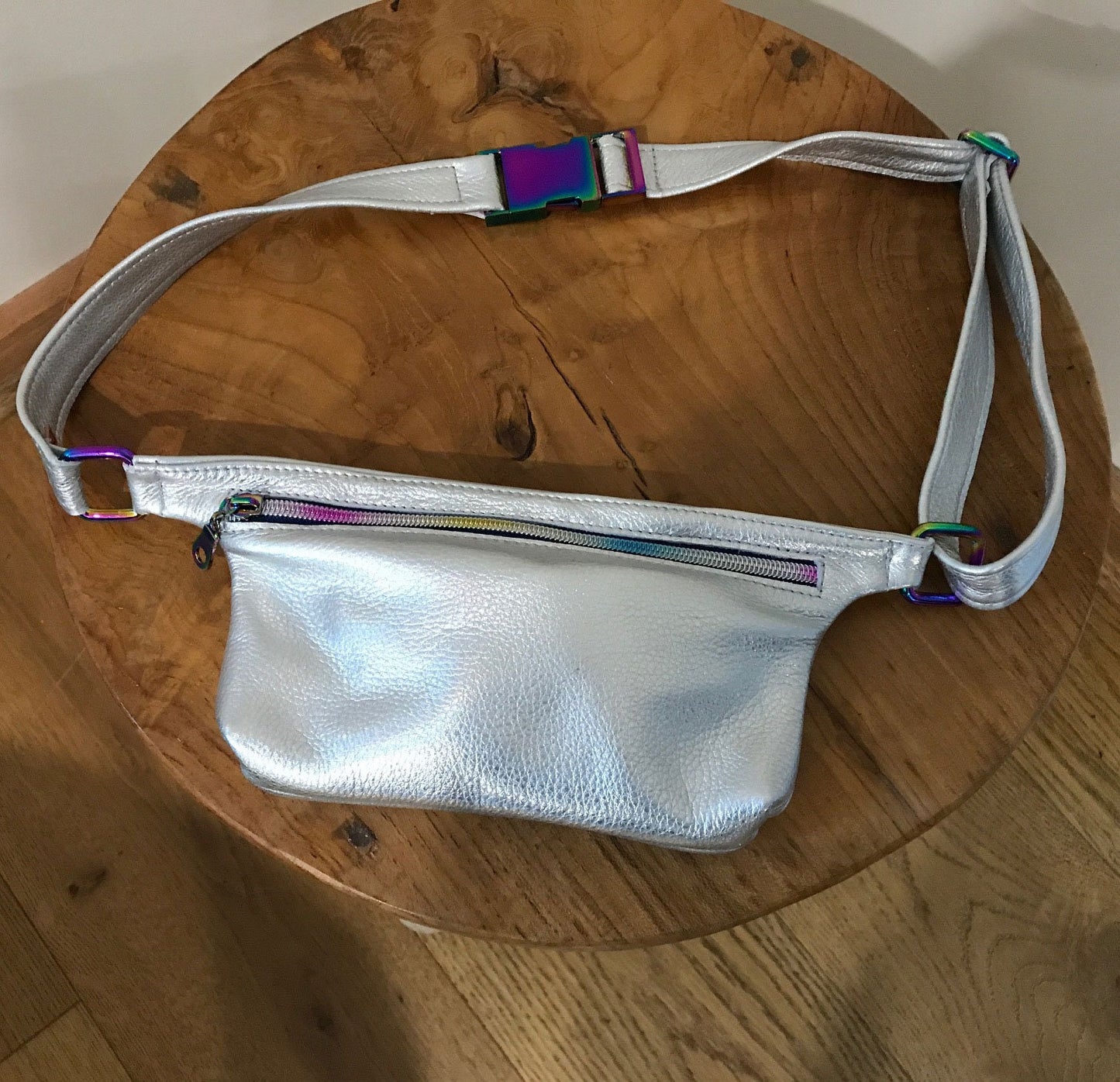 Silver fanny pack with colorful straps on a wooden surface