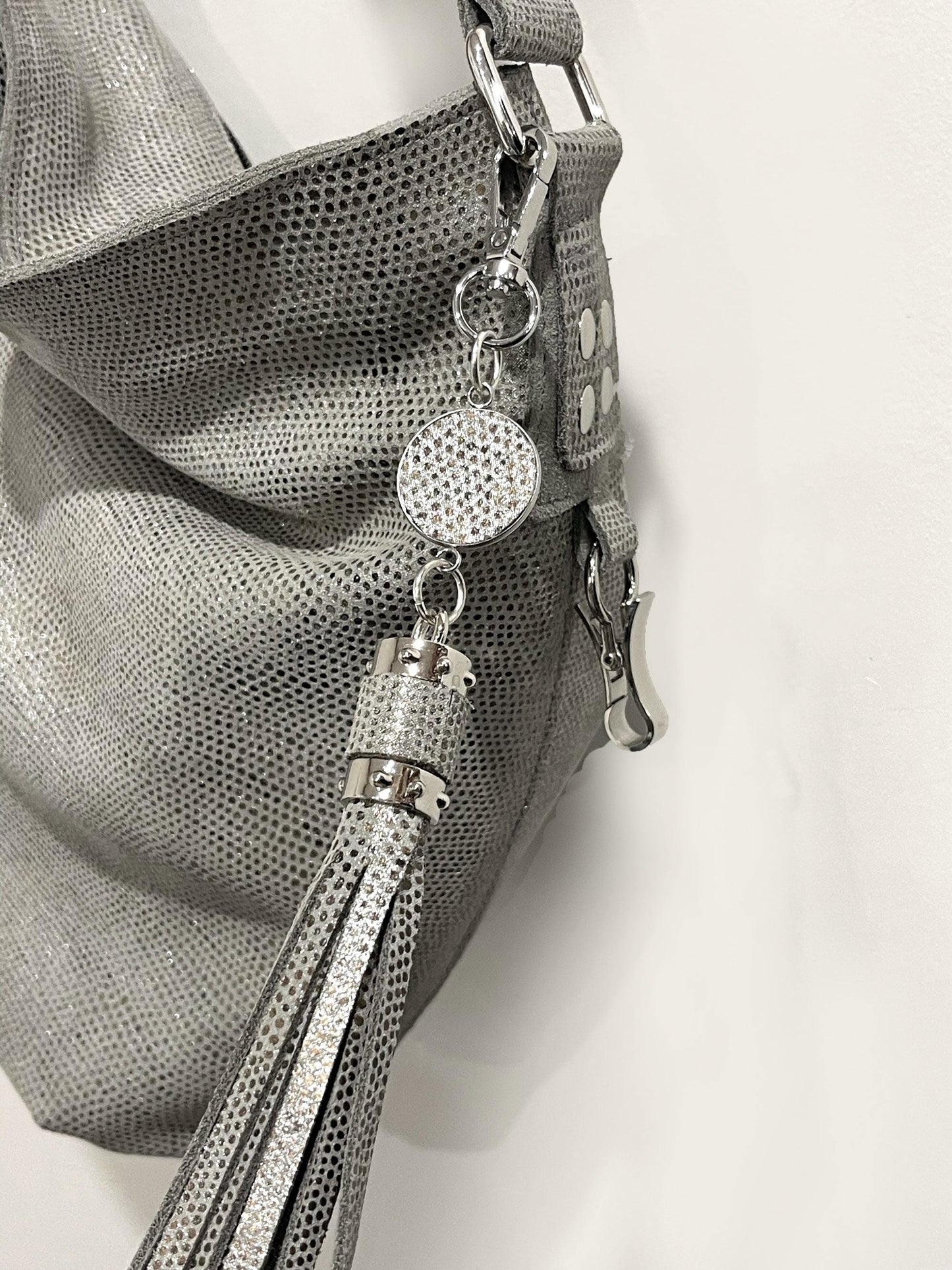 close up of a silver pearl handbag with decorative charm and tassel on a white background