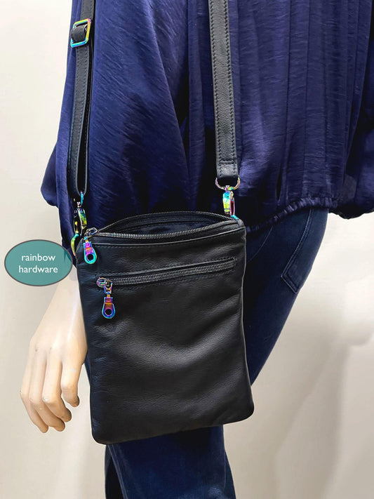 Black crossbody bag with rainbow hardware worn by a person in a blue outfit.