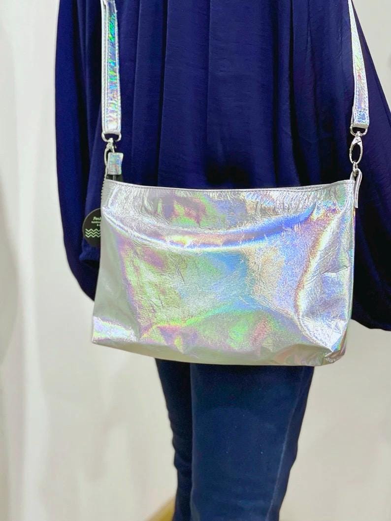 Holographic crossbody bag worn by a person with a plain background
