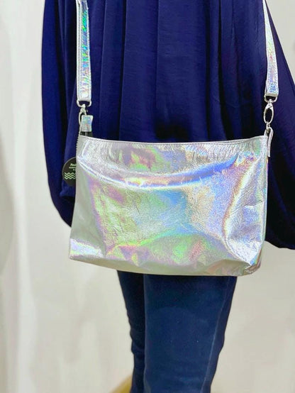 Holographic crossbody bag worn by a person with a plain background