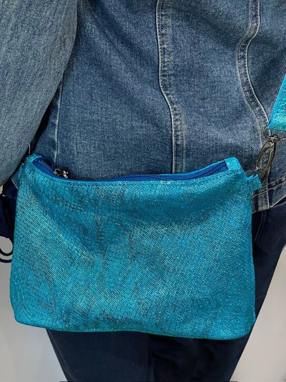 Blue denim bag held by a person wearing a denim jacket and jeans.
