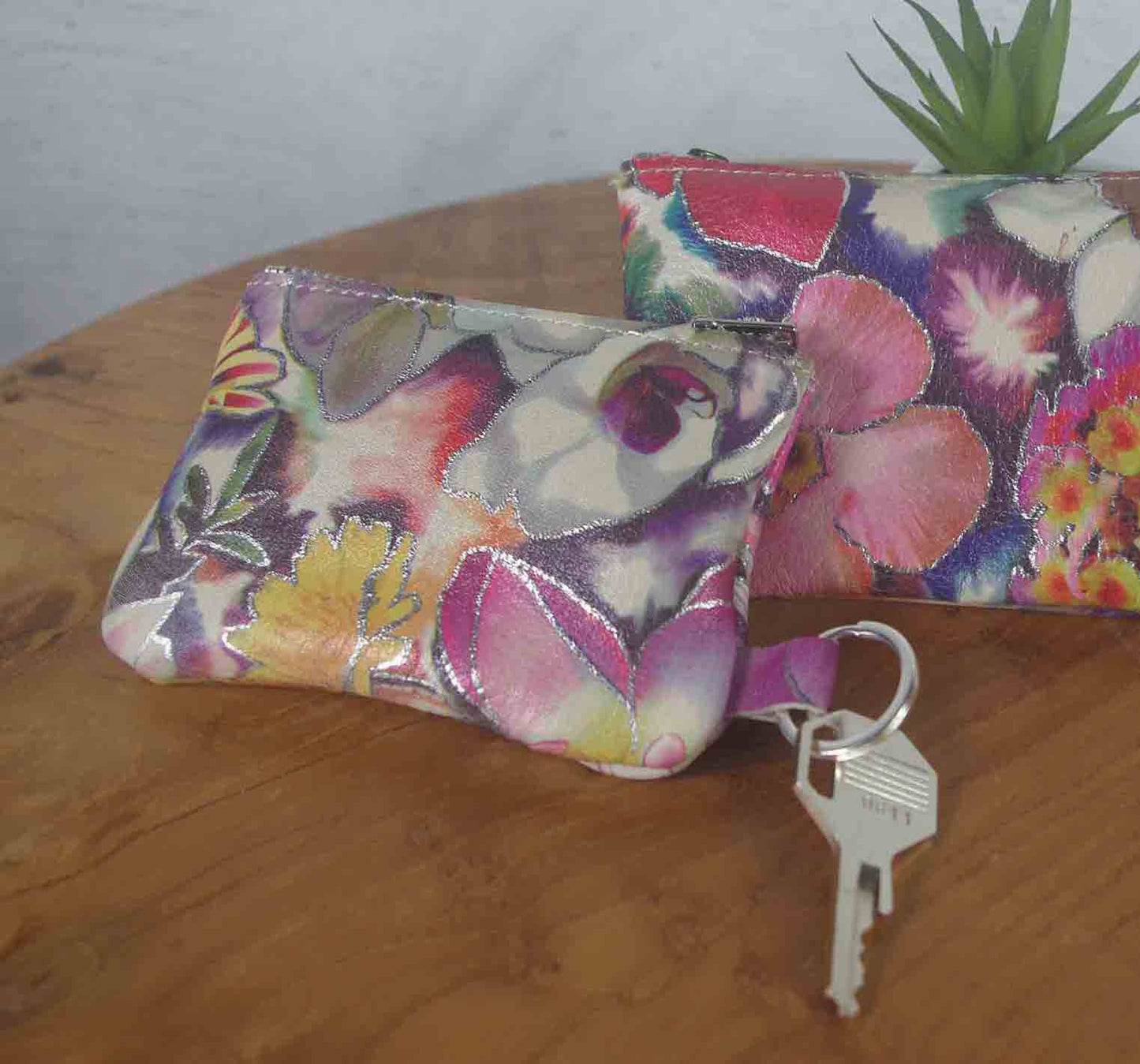 Floral-patterned pouches on a wooden surface with keys.