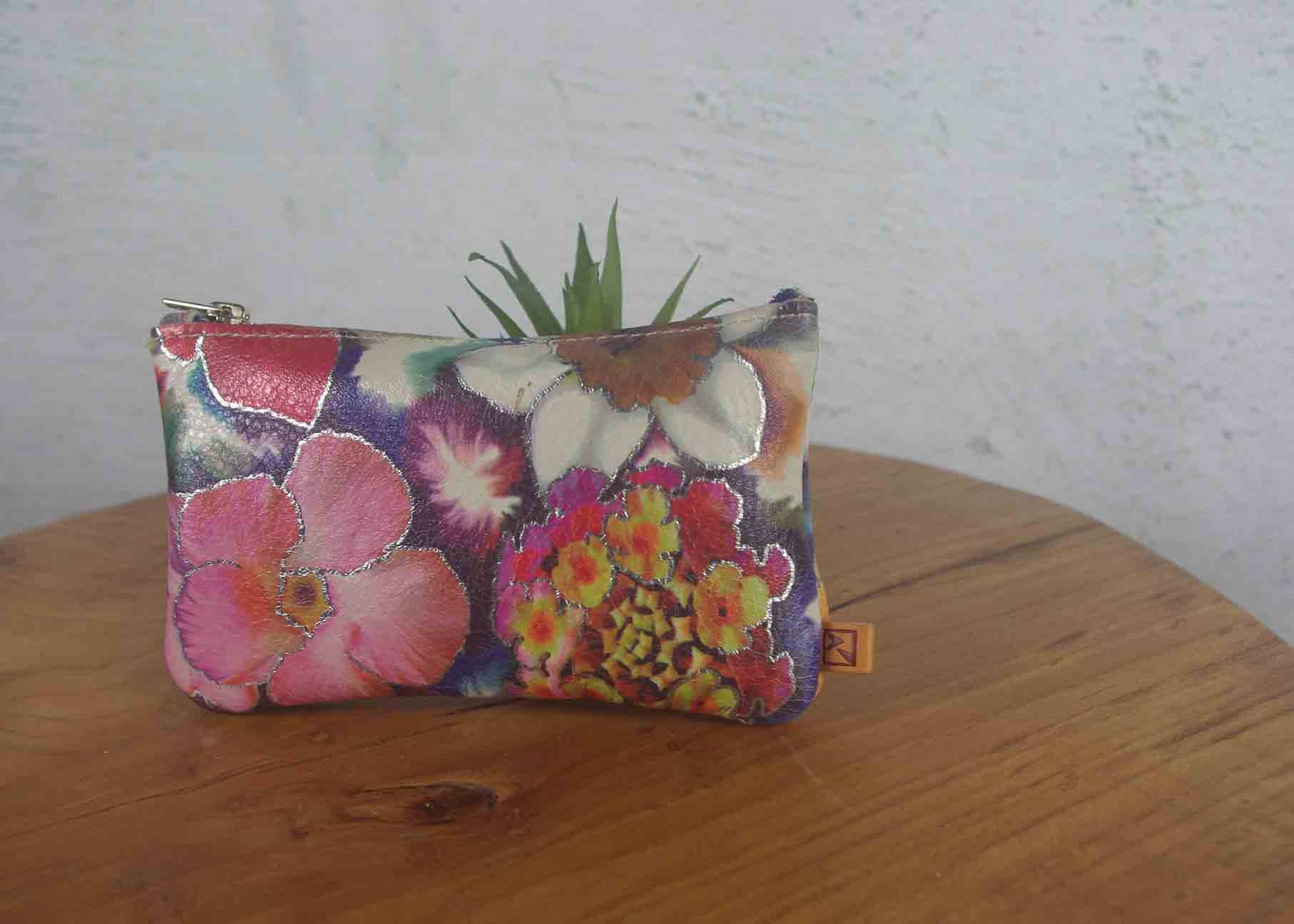Floral-patterned pouch on a wooden surface with a white wall background