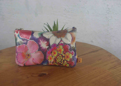 Floral-patterned pouch on a wooden surface with a white wall background
