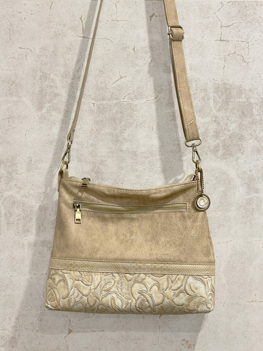 Beige handbag with floral pattern on a textured gray background