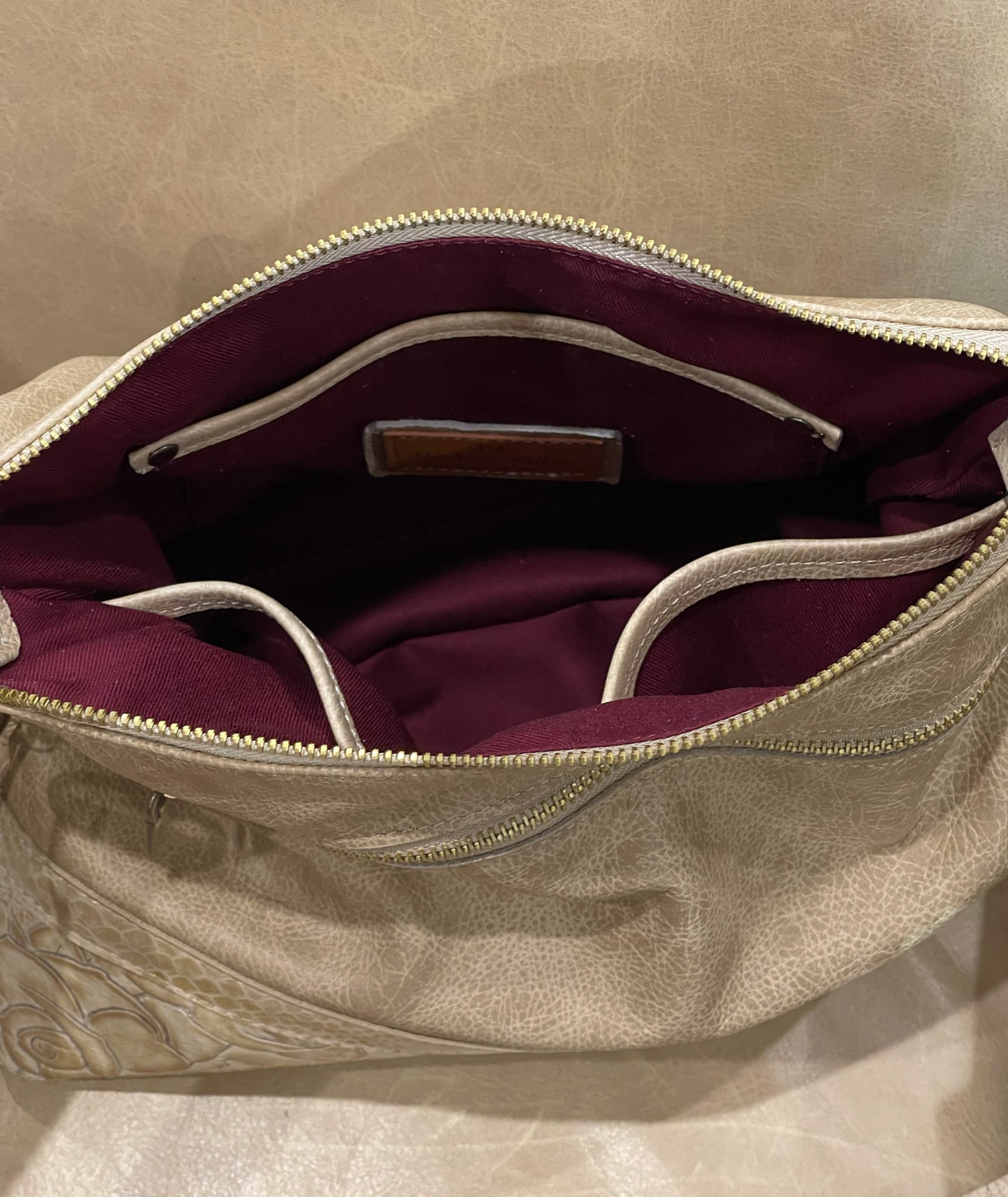 Open beige handbag with burgundy interior lining and slip pockets