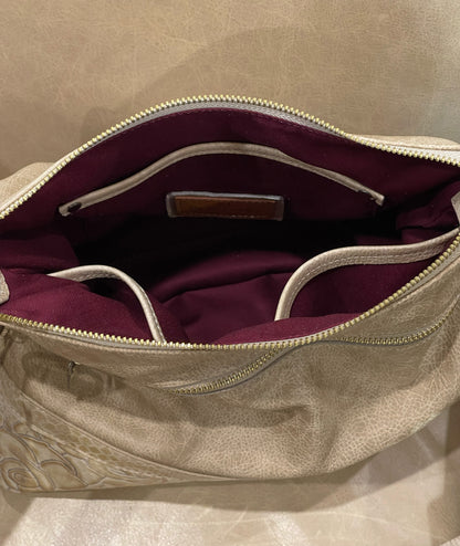 Open beige handbag with burgundy interior lining and slip pockets